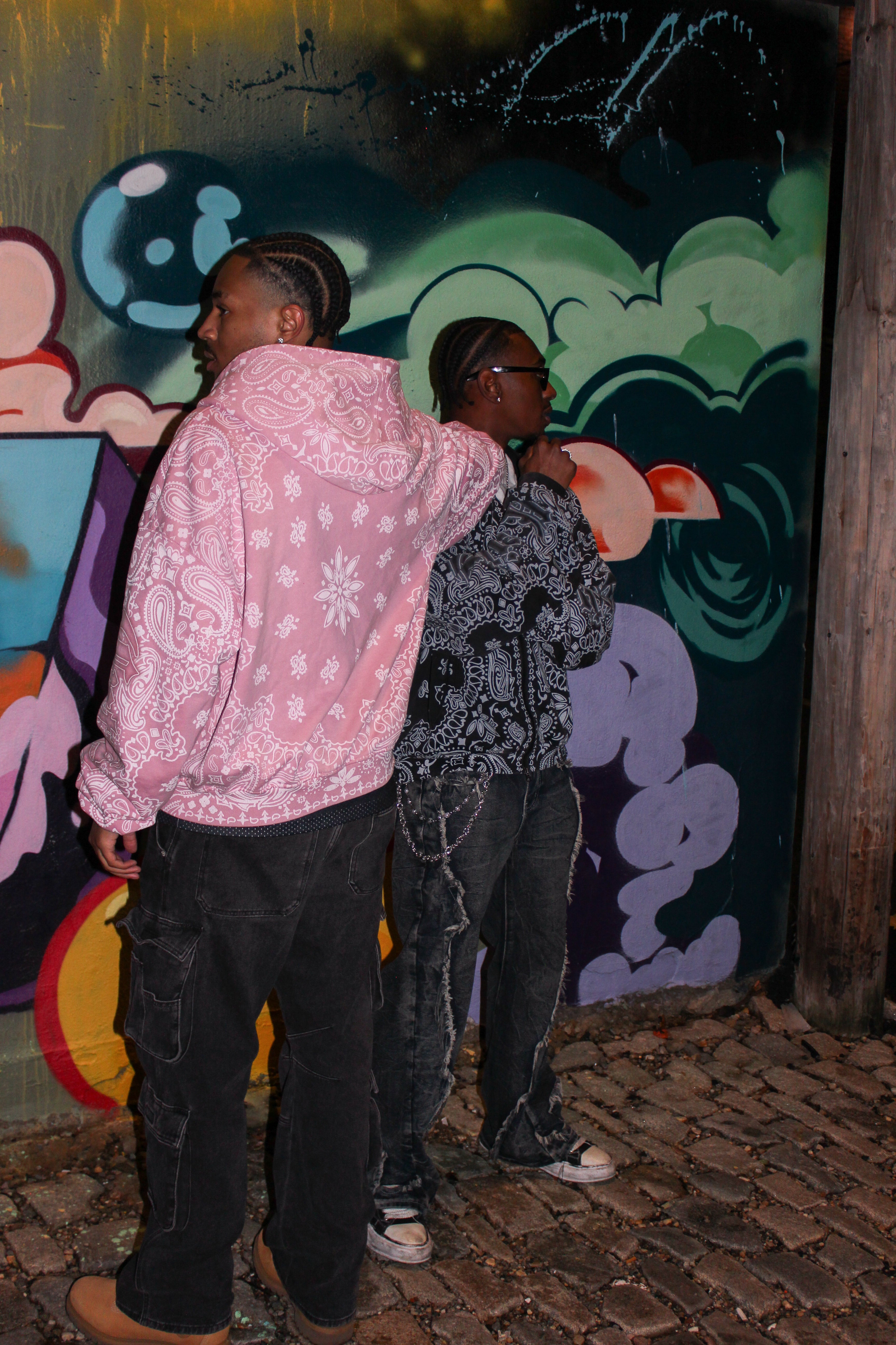 Two people standing in front of a colorful graffiti wall.